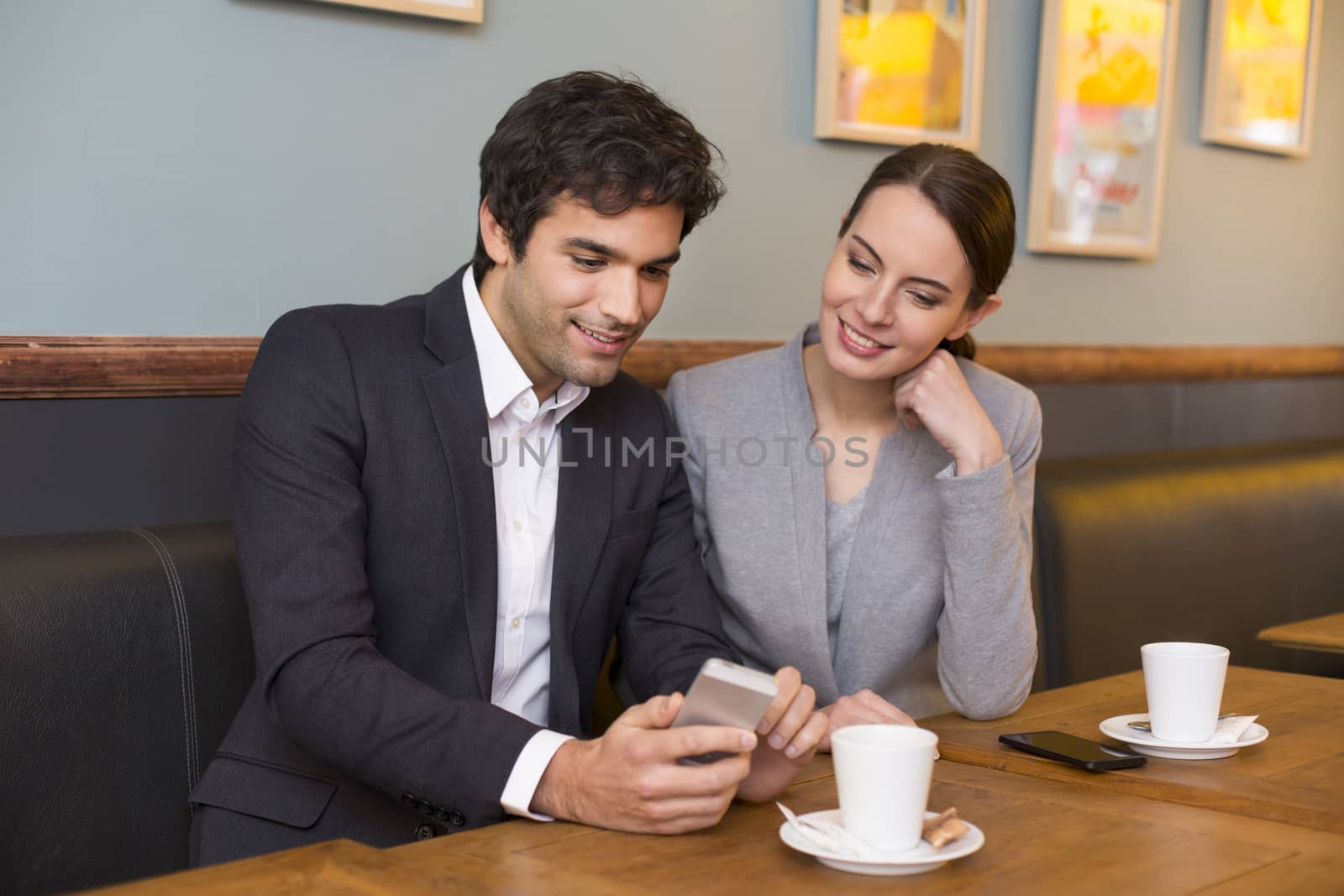 Young couple using a smartphone in restaurant by LDProd