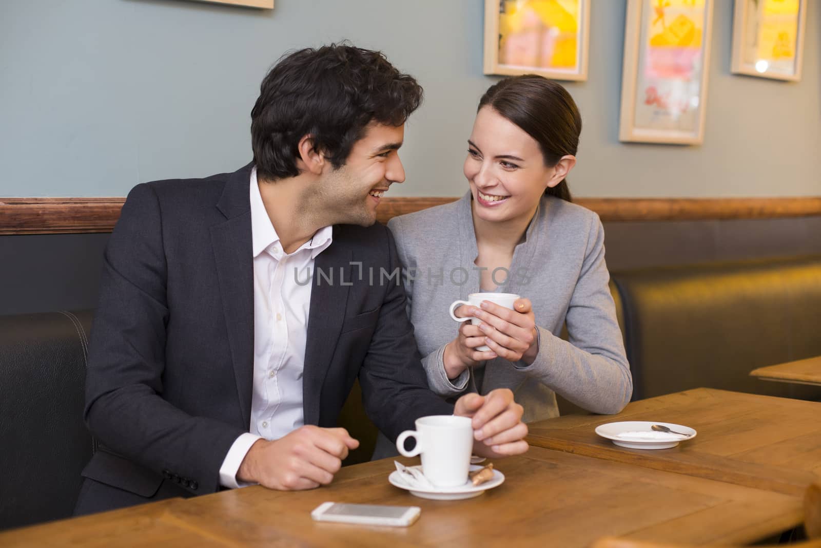 Cheerful couple flirting at coffee bar table by LDProd