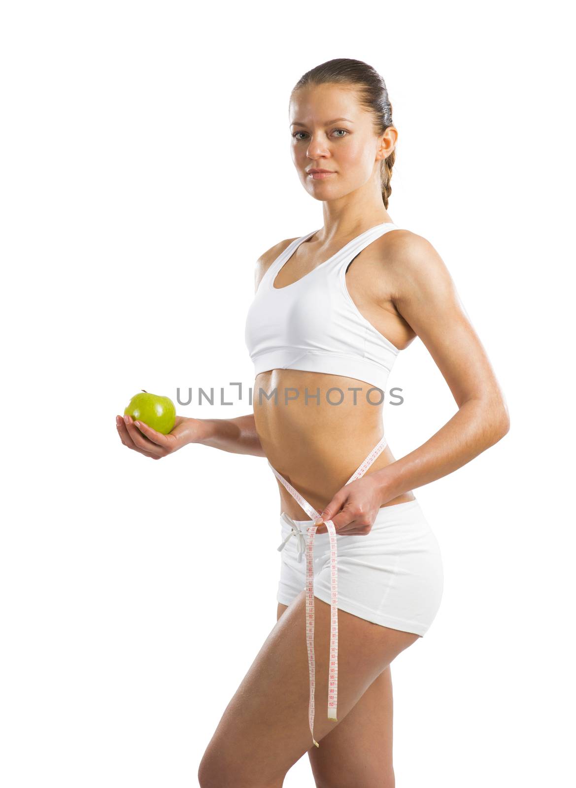 young athletic girl measuring waist measuring tape and holding a green apple, concept of healthy eating, isolated on white background