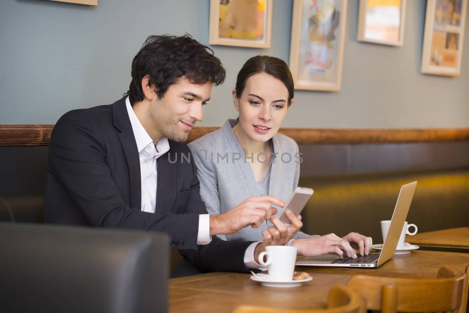 Young couple working on laptop at coffee bar by LDProd