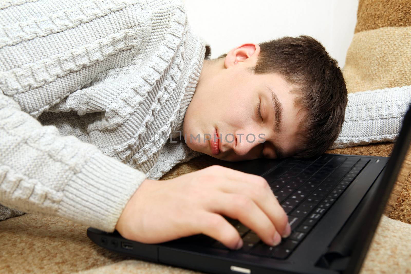 Tired Teenager falling asleep with Laptop on Sofa