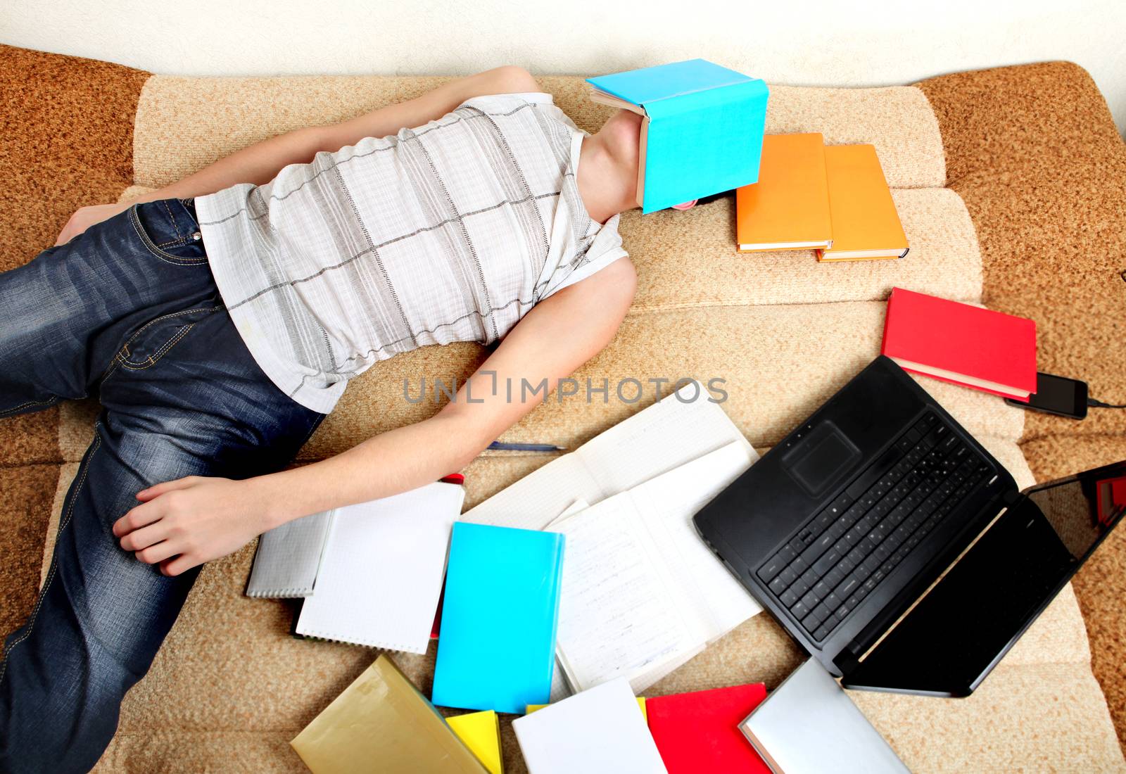 Tired Teenager sleeps after Learning on the Sofa with the Books