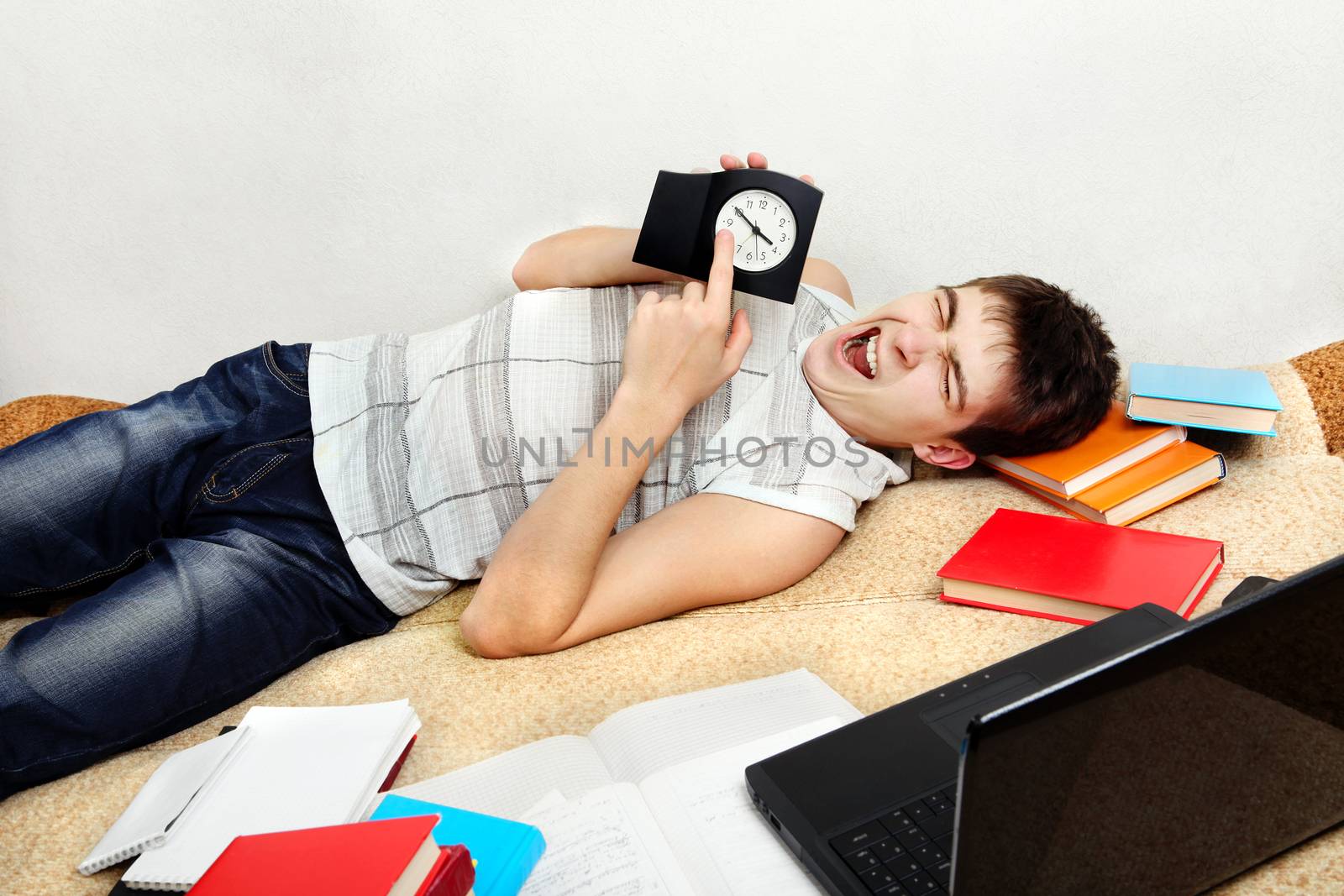 Tired Student Yawning on the Sofa and pointing on the Clock