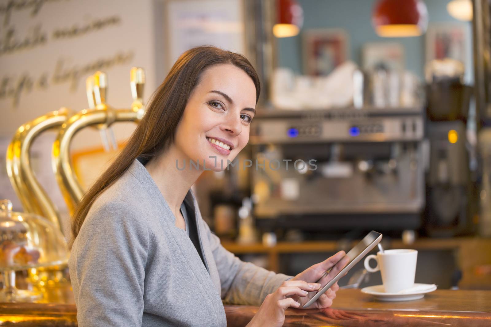 Beautiful young woman using her tablet pc in coffee bar, looking by LDProd