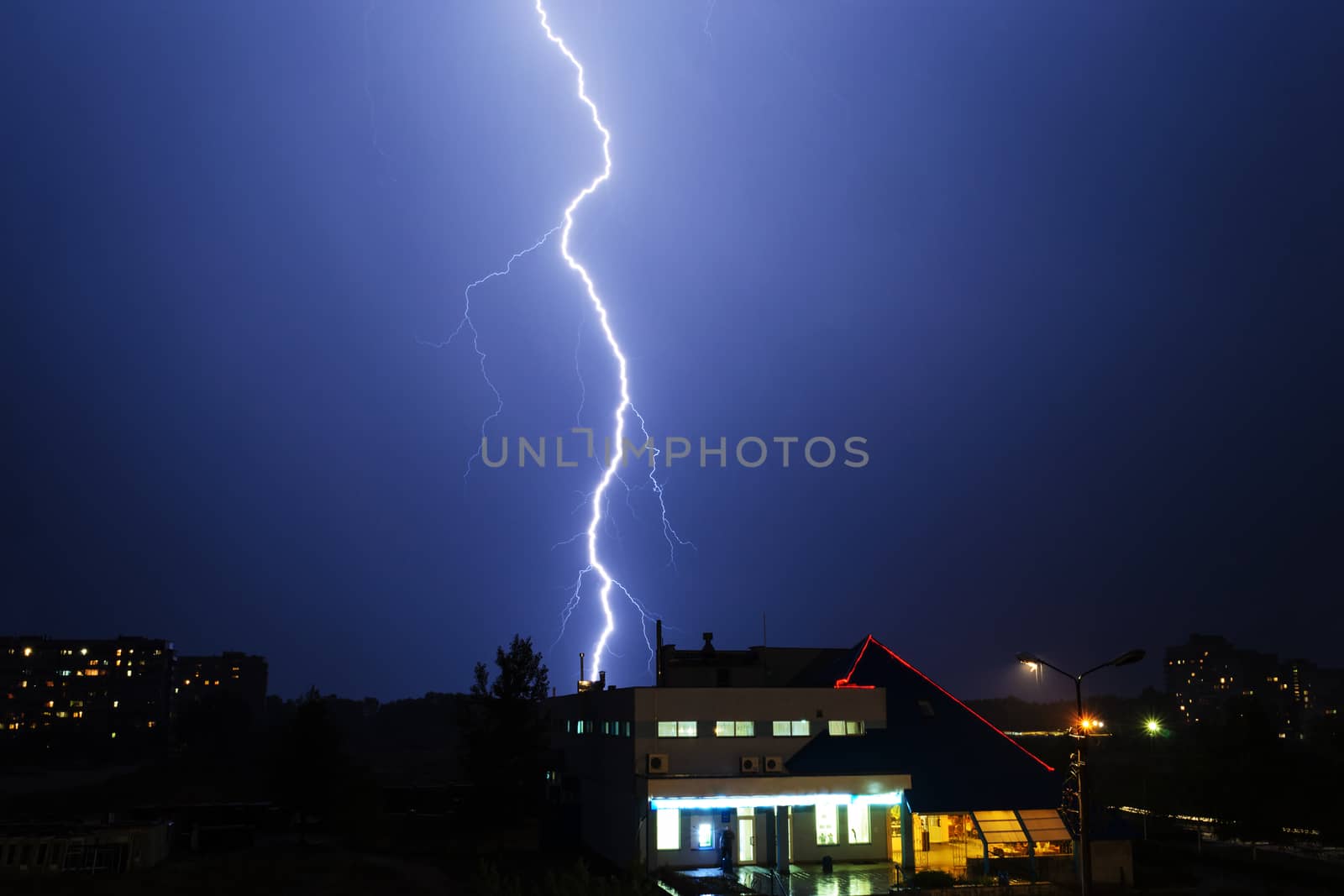 Severe lightning storm with rain over a city buildings at night
