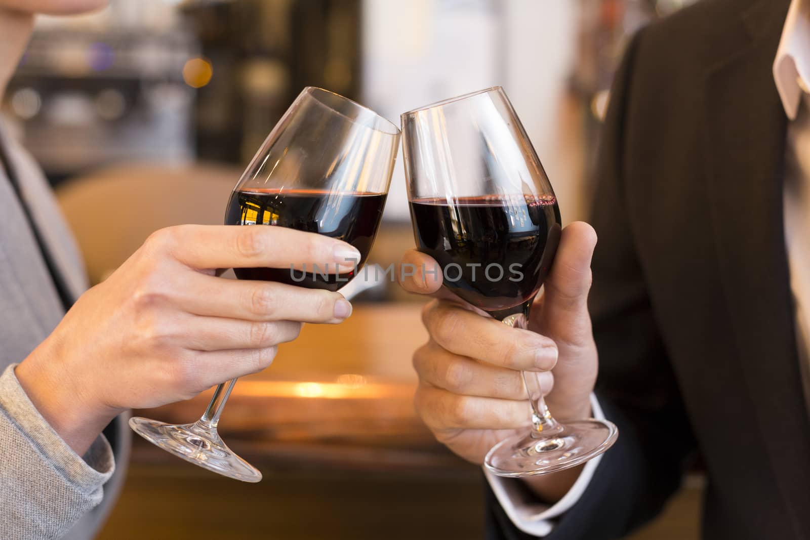 Close Up of Couple Toasting with red wine glass in restaurant by LDProd