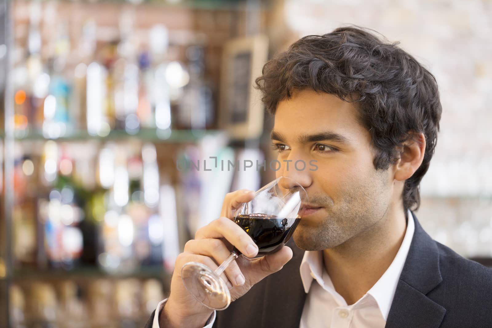 Handsome man drinking a glass of red wine in bar by LDProd