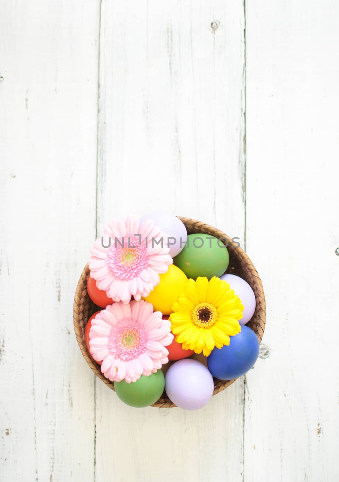 Easter eggs inside a wicker basket with daisies
