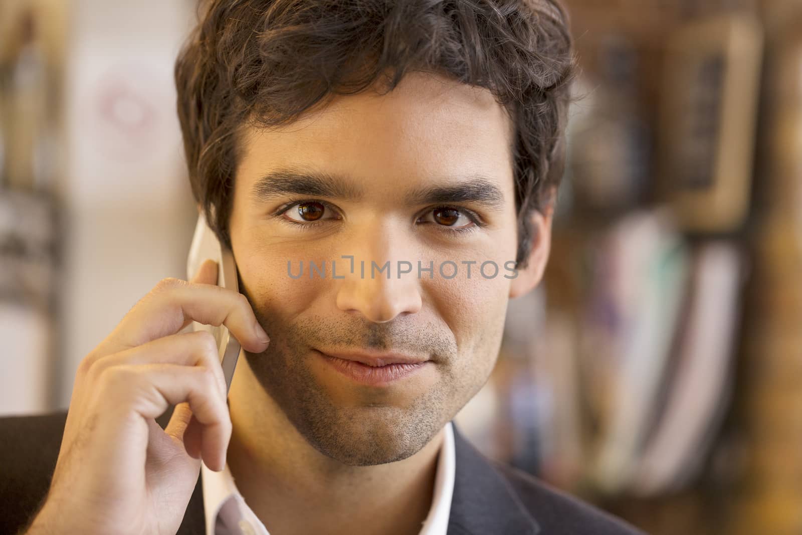Handsome man calling with a cell phone in coffee bar, looking ca by LDProd