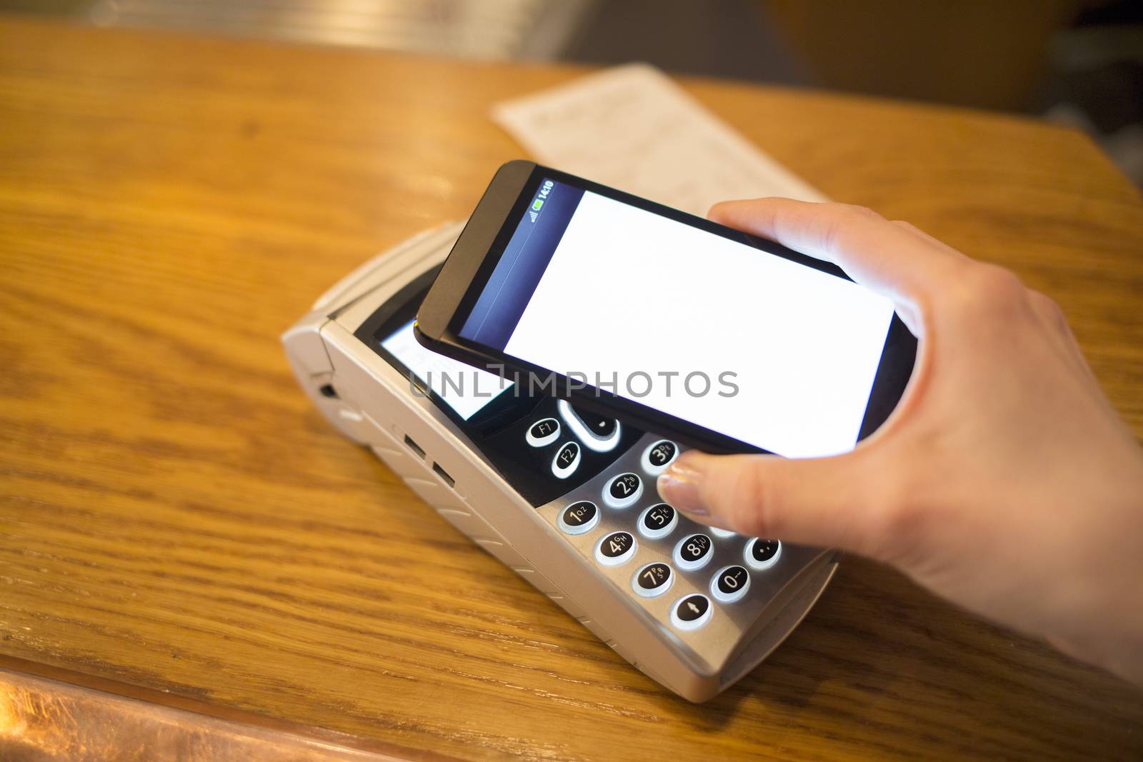 Woman paying with NFC technology on mobile phone, restaurant, sh by LDProd