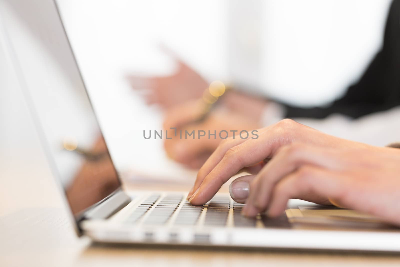 Woman using laptop in office during a meeting. Close-up hands by LDProd