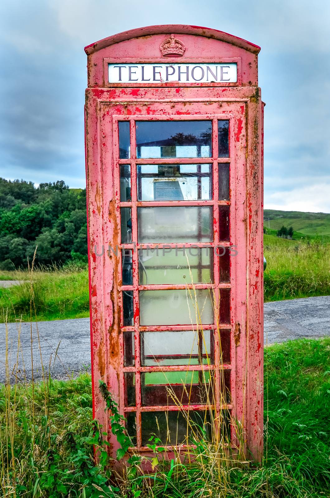 Detail of old red English phone booth in countryside, United Kingdom