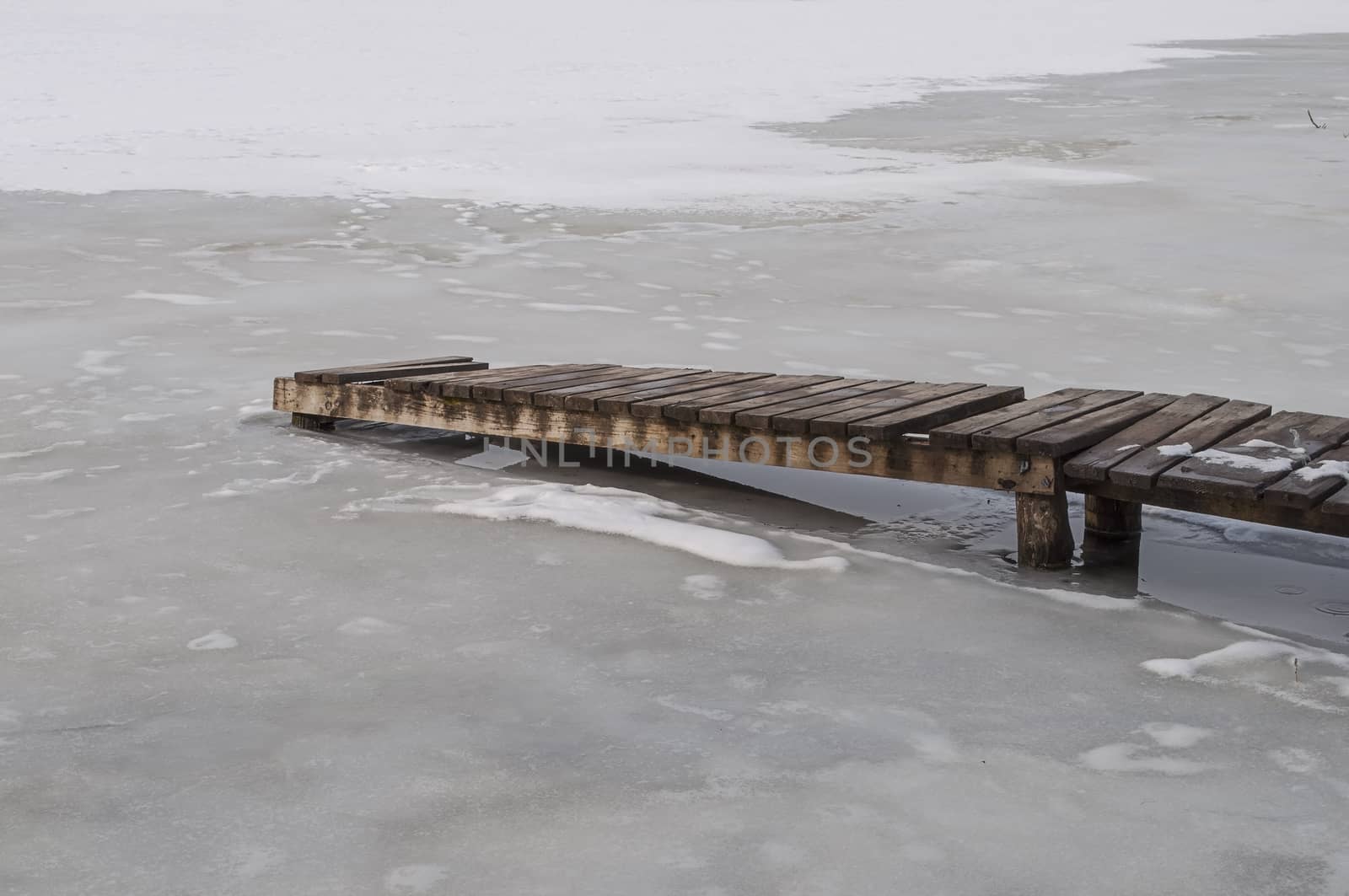 Wooden footbridge on a frozen pond, early spring