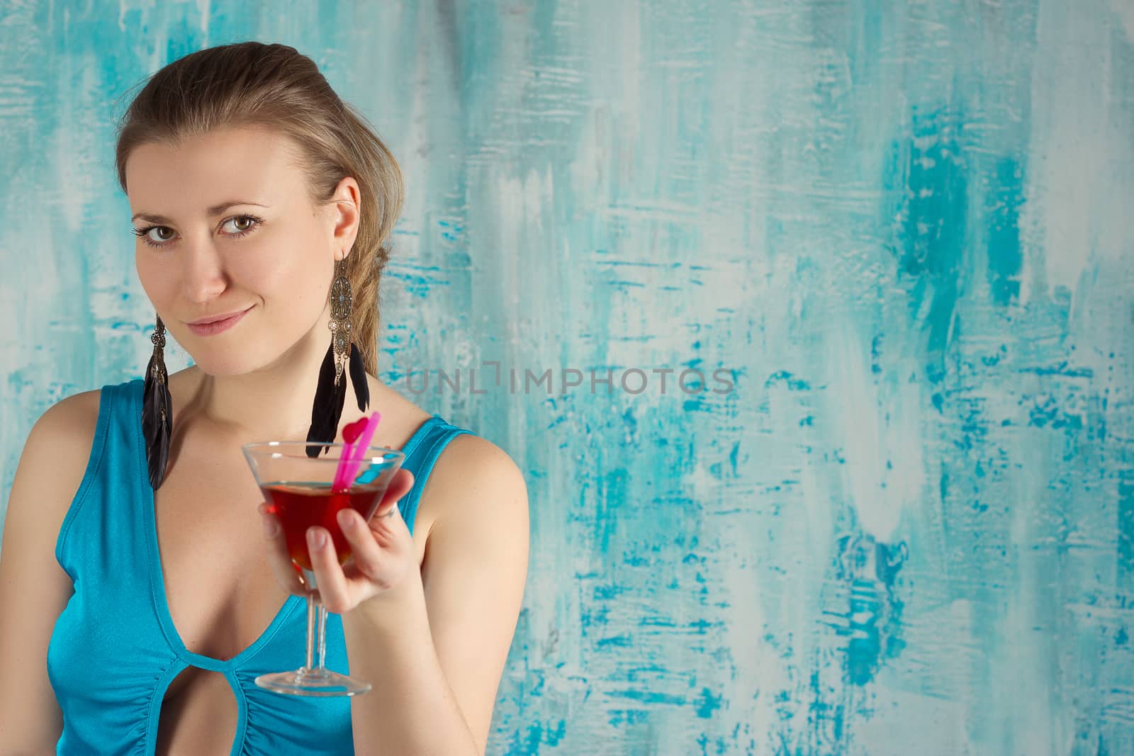 Happy beautiful woman holding a tropical cocktail with sunglasses on bright background