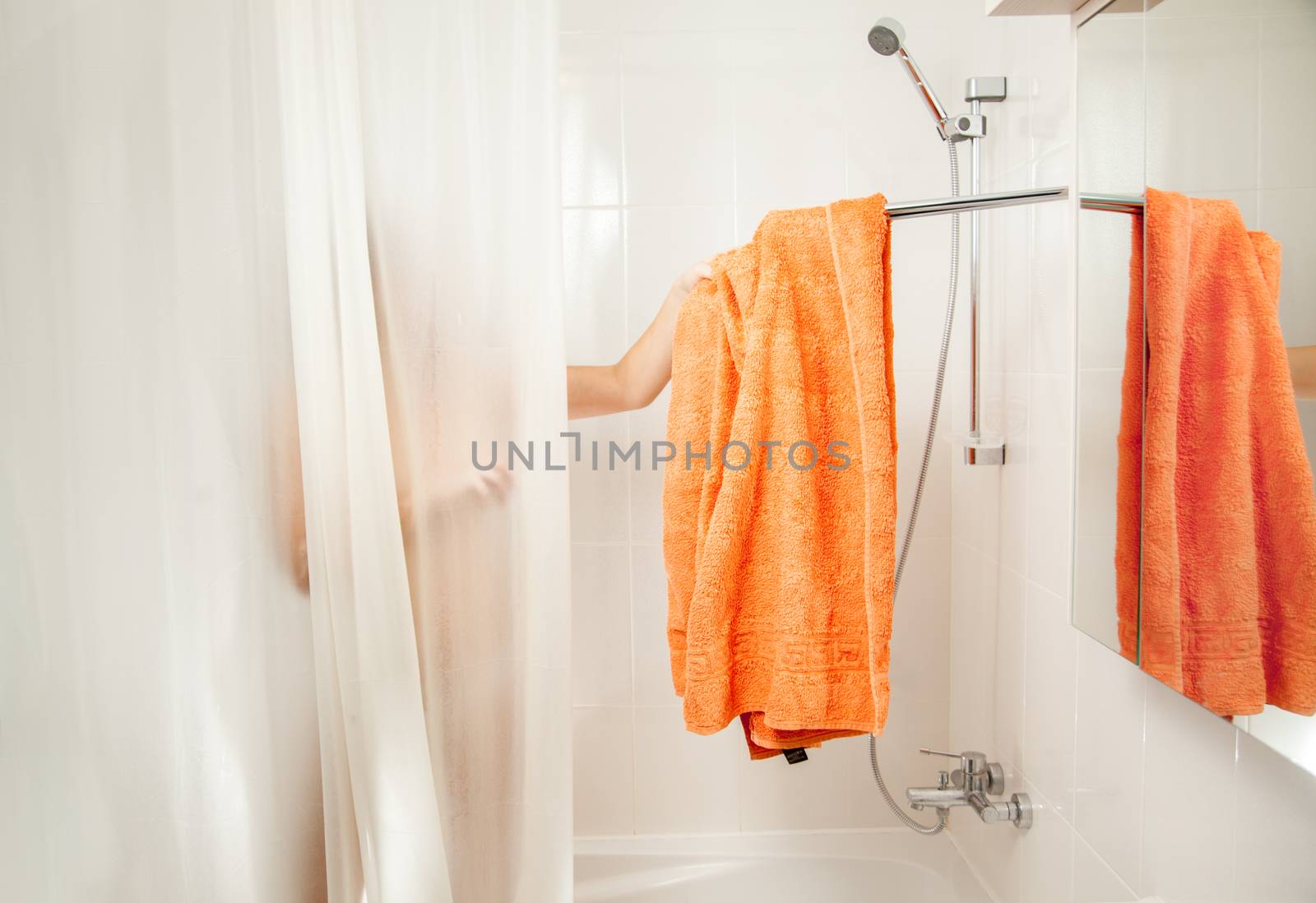Woman in shower taking off orange towel from hook