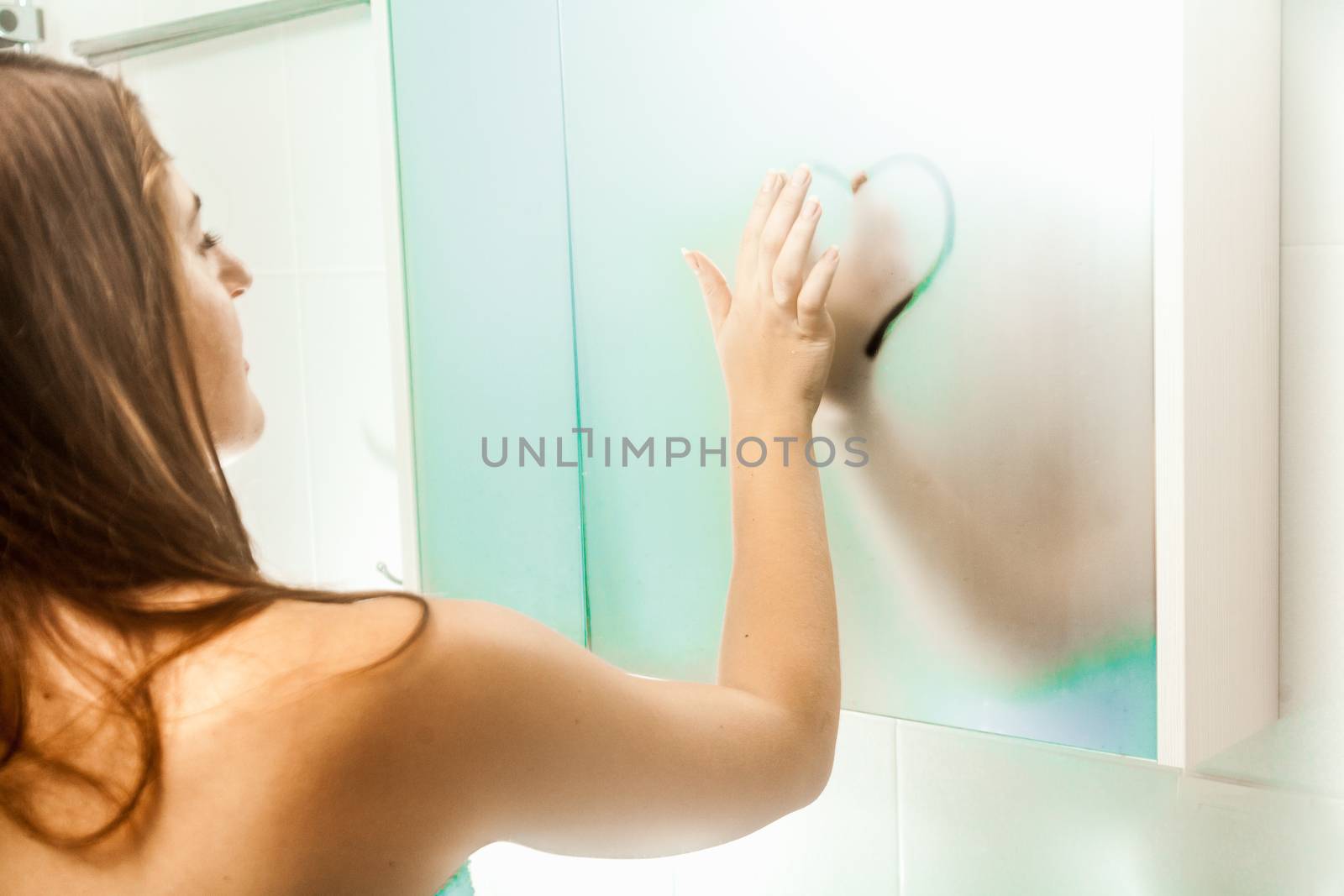 nude woman drawing heart on steamy mirror by Kryzhov