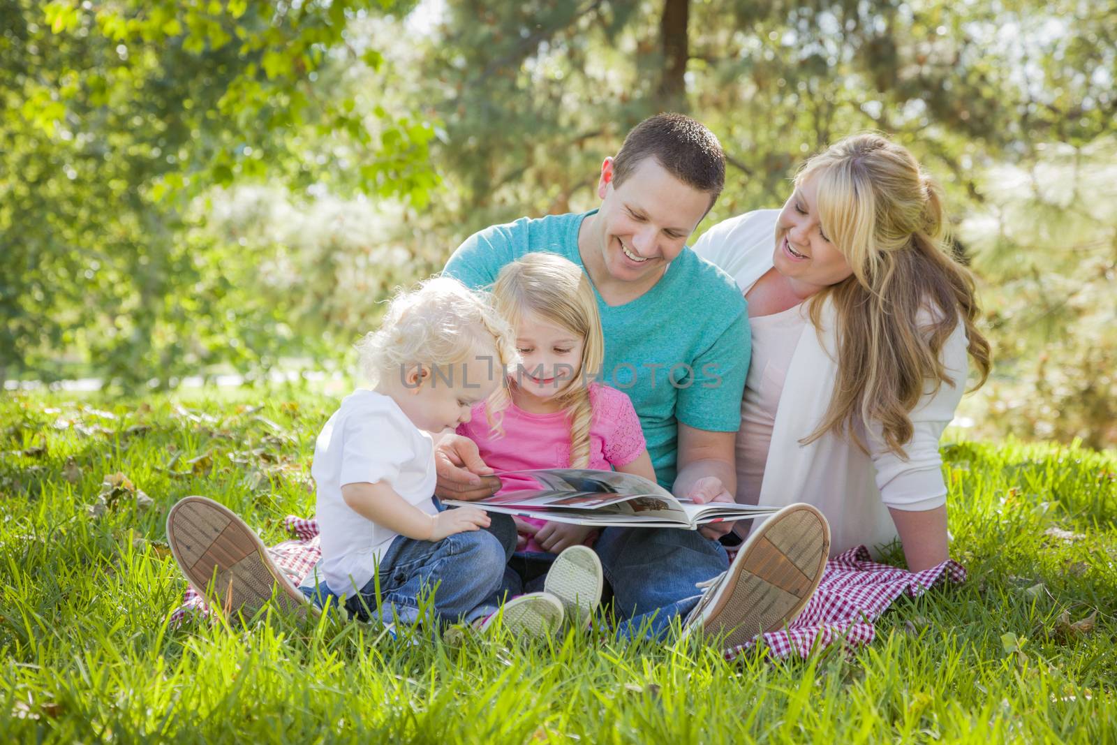 Young Family Enjoys Reading a Book Together in the Park.
