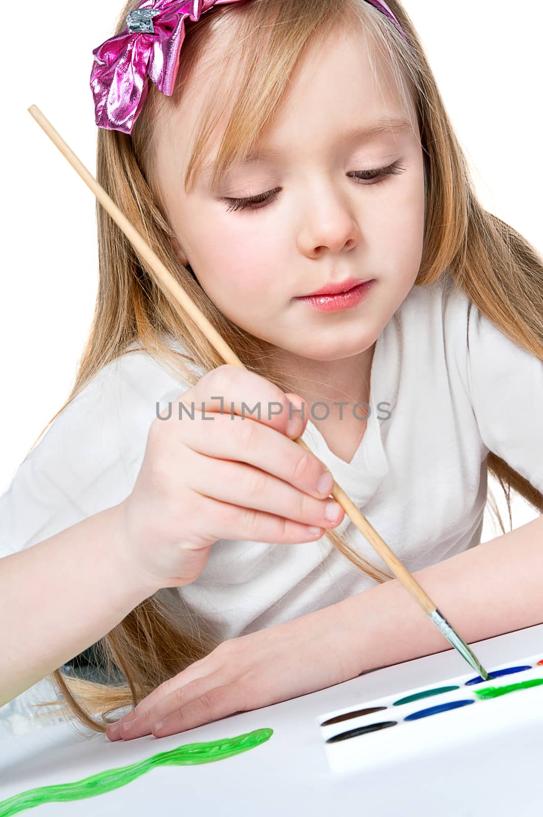pretty little girl paints with a brush on paper