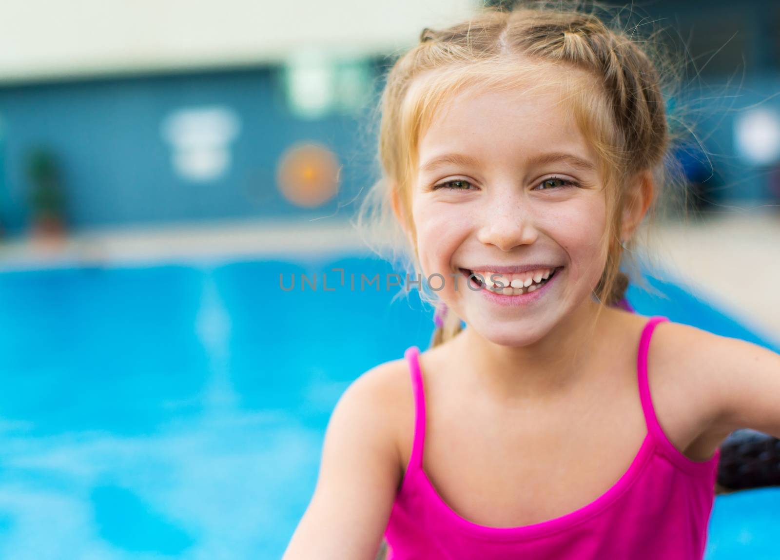 little smiling girl near a swimming pool