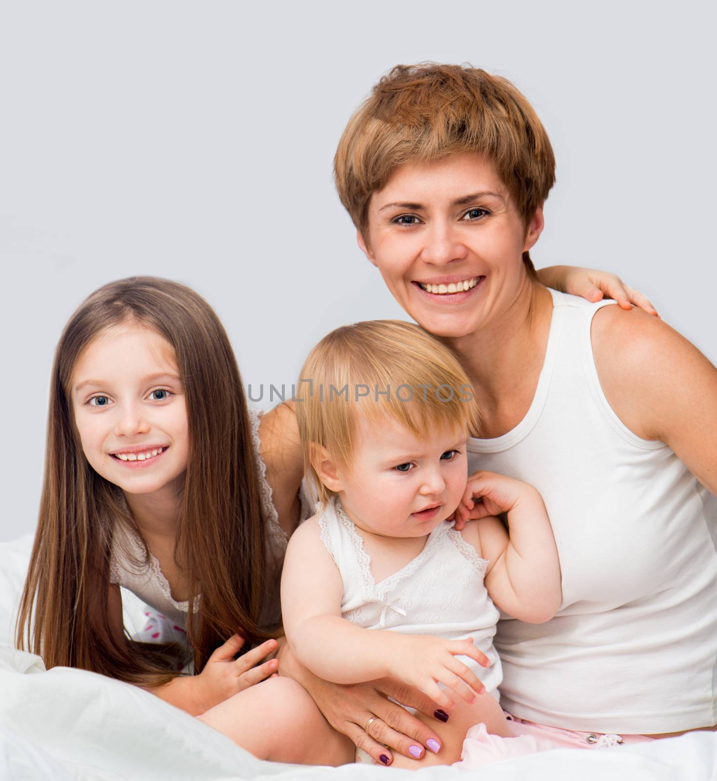 Happy mother with her вЂ‹вЂ‹son and daughter sitting on a bed.
