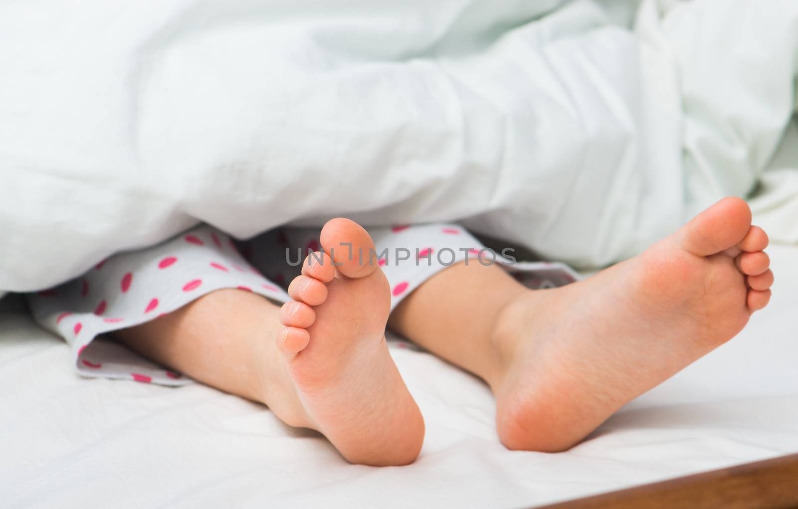 Baby feet on a bed under a white blanket