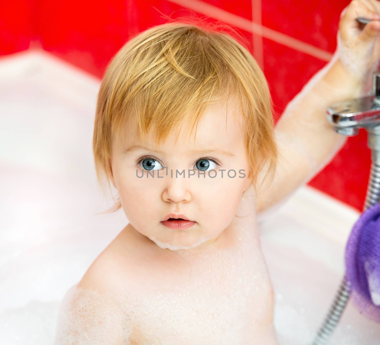 cute little baby is taking a shower