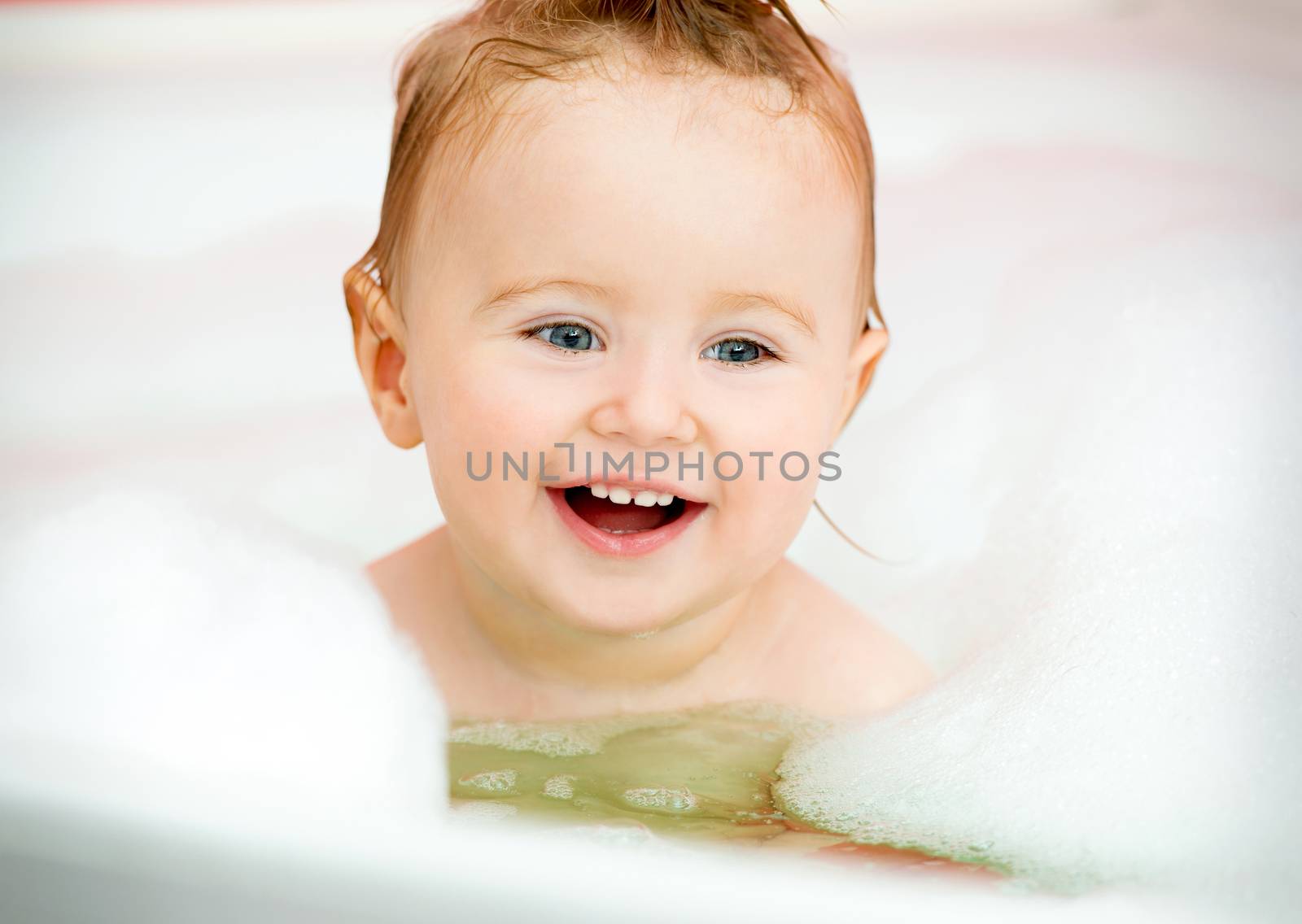 little smiling baby in a bubble bath