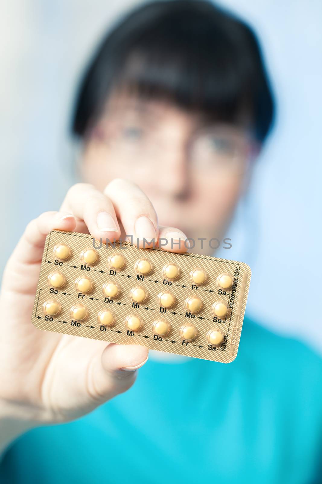 Young woman holds birth control pills by motorolka