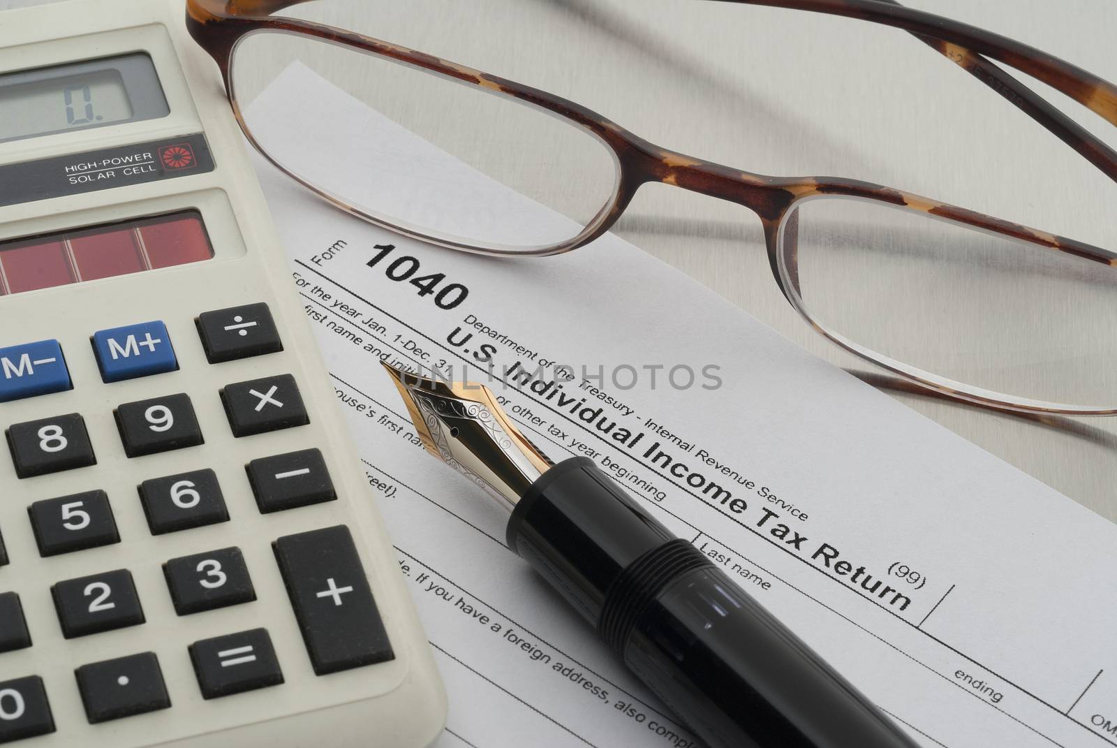 Tax preparation with fountain pen, calculator, glasses and forms