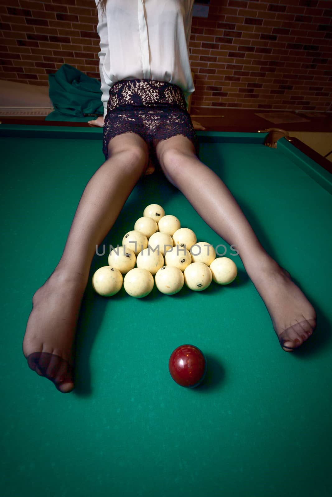 Sexy woman in stockings sitting on billiard table