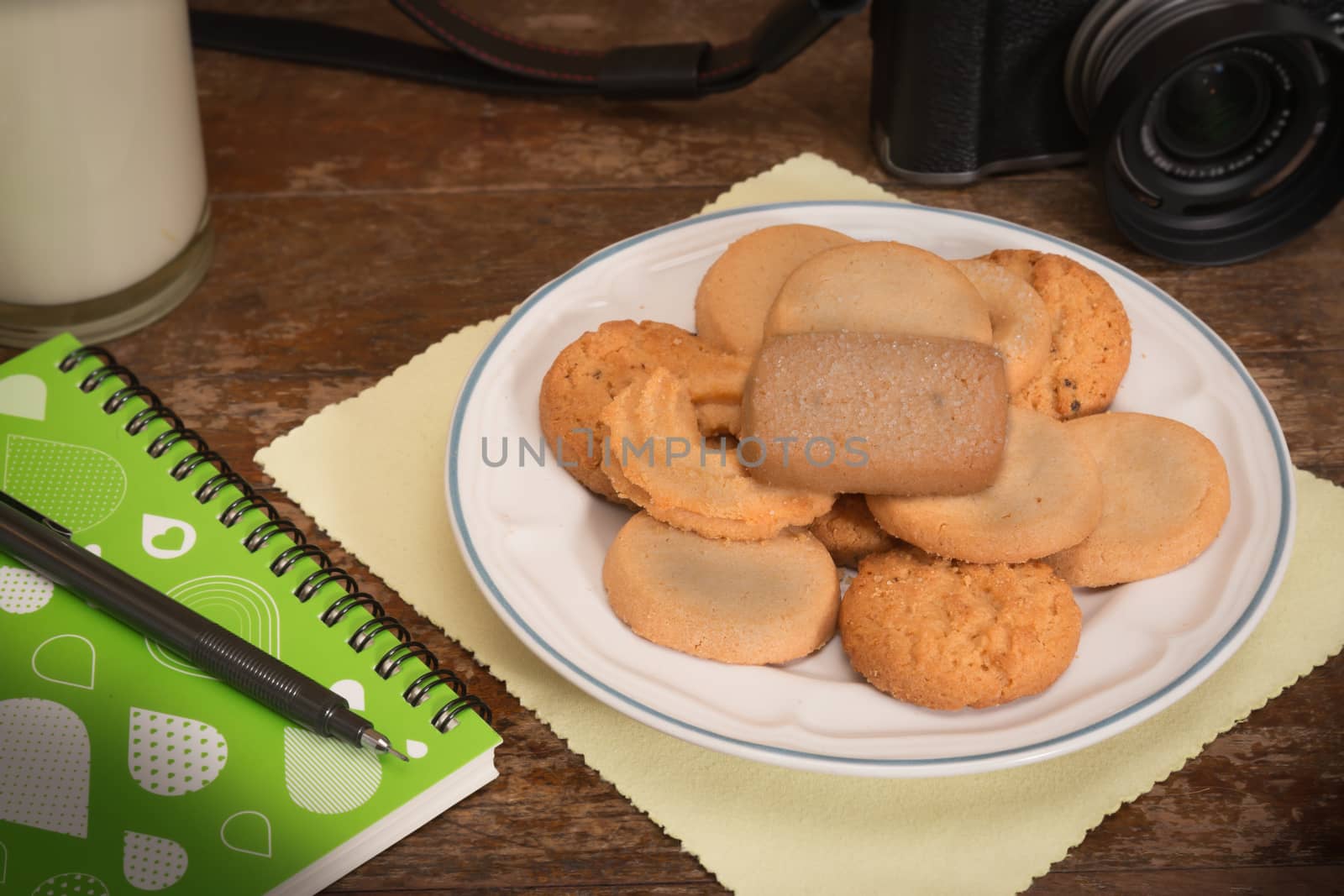 cookies multiple flavors, Notebook, camera, milk On wooden table