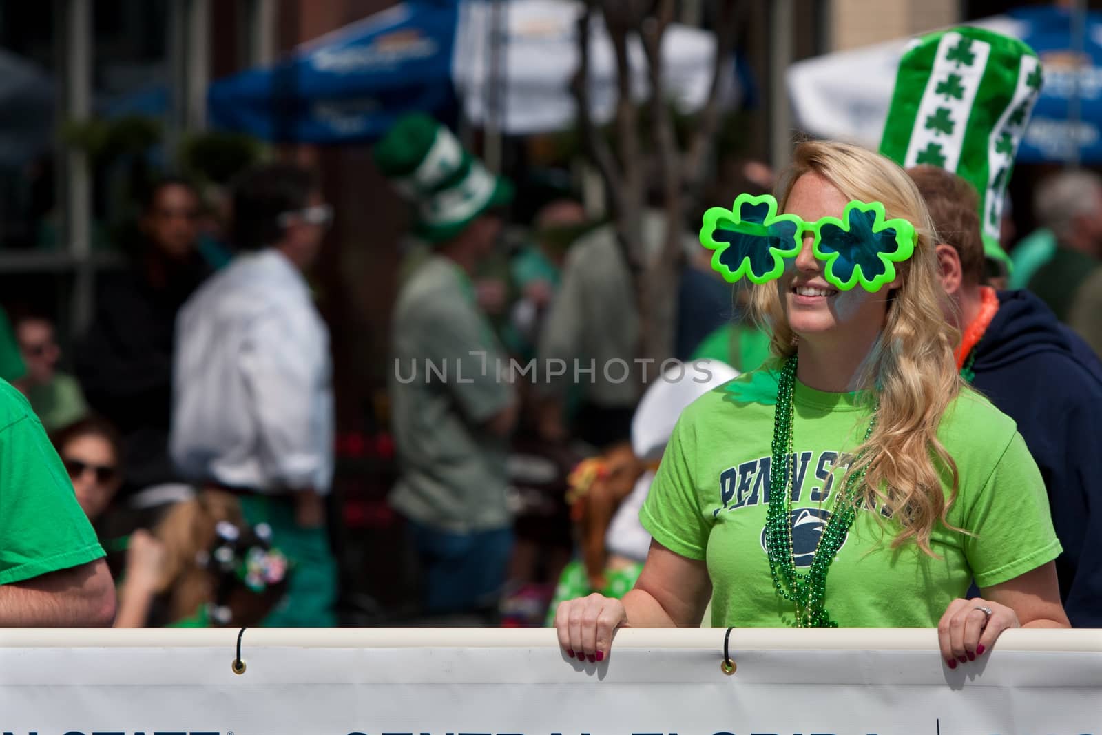 Atlanta, GA, USA - March 15, 2014:  A woman wearing shamrock sunglasses carrries a banner down Peachtree Street as part of the St. Patrick's parade. 