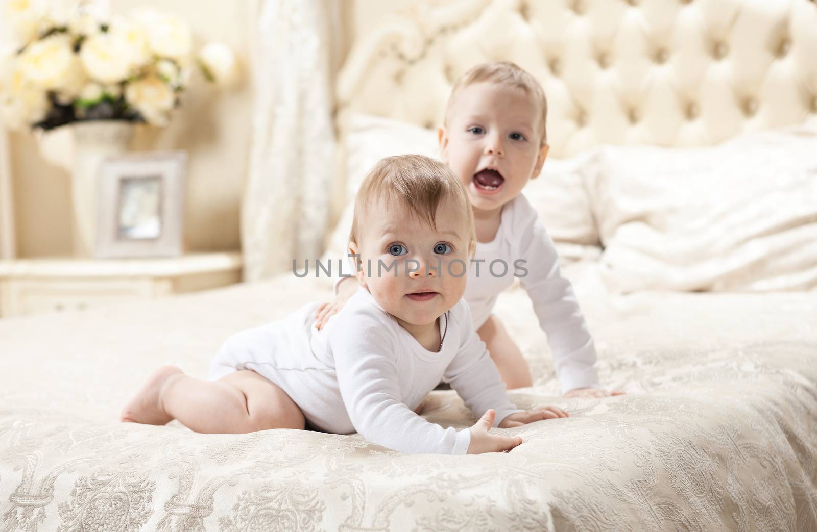 Two baby boys playing on bed by photobac