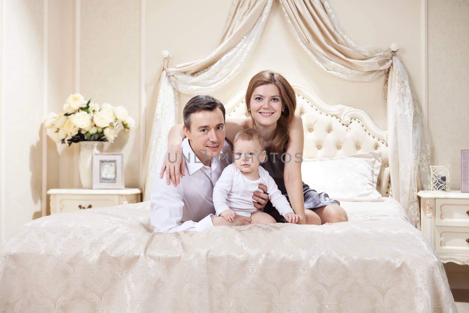 Young happy family with a baby on bed at home