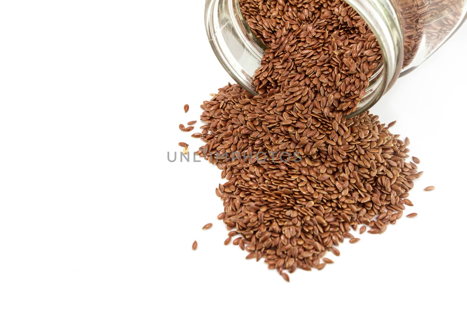 Heap of flaxseed in glass bottle isolated on white background 
