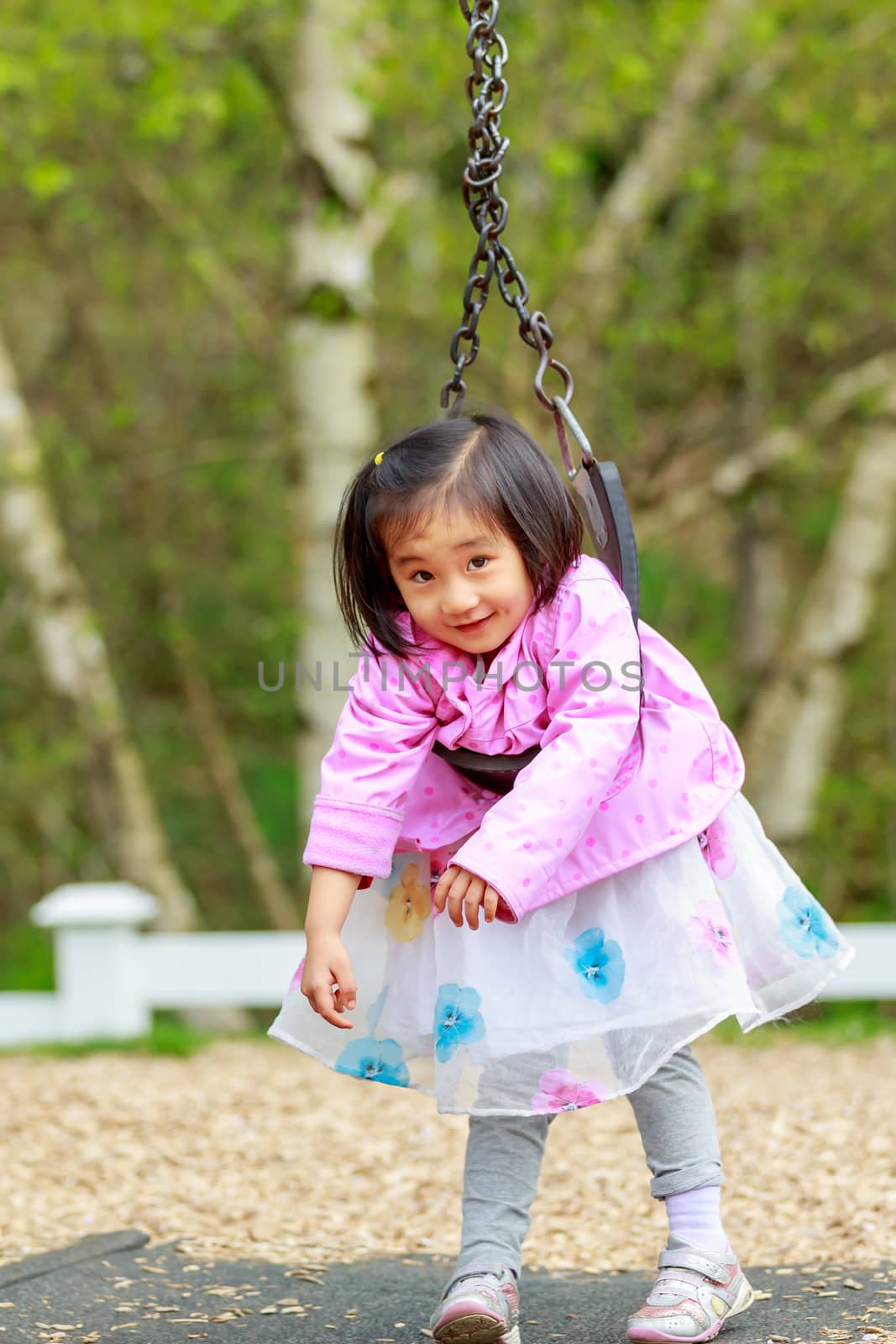 Adorable girl plays in the playground, twisted on the swing