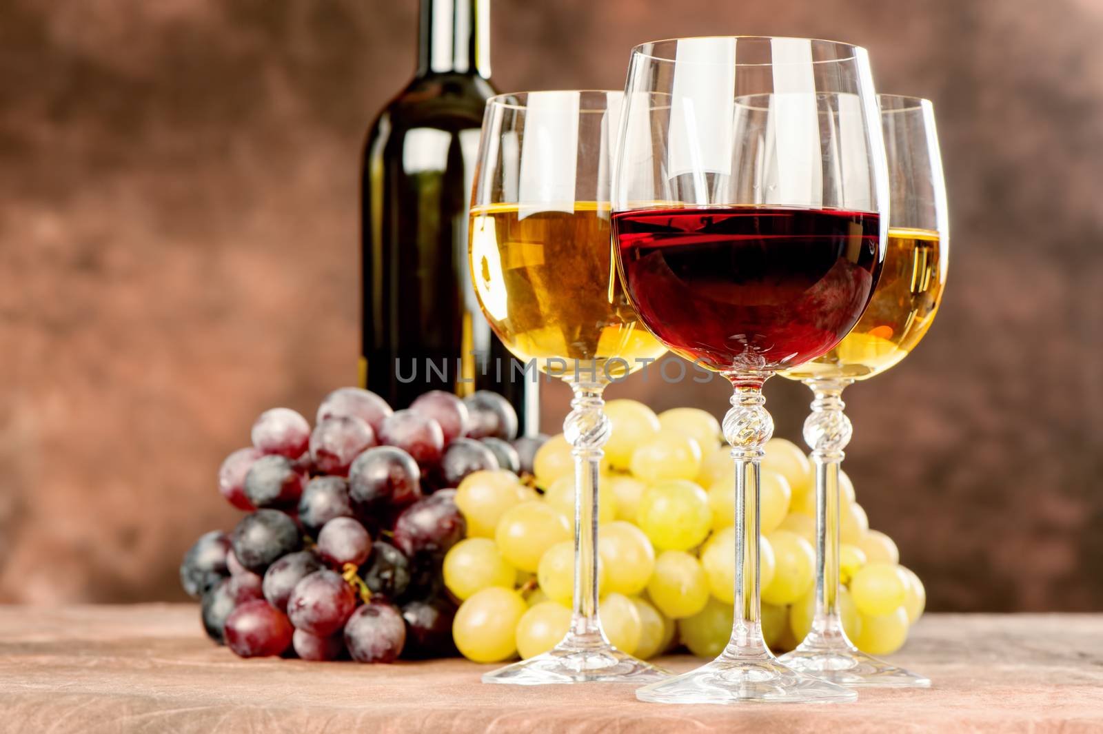 cups of red and white wine in front of grape and bottle