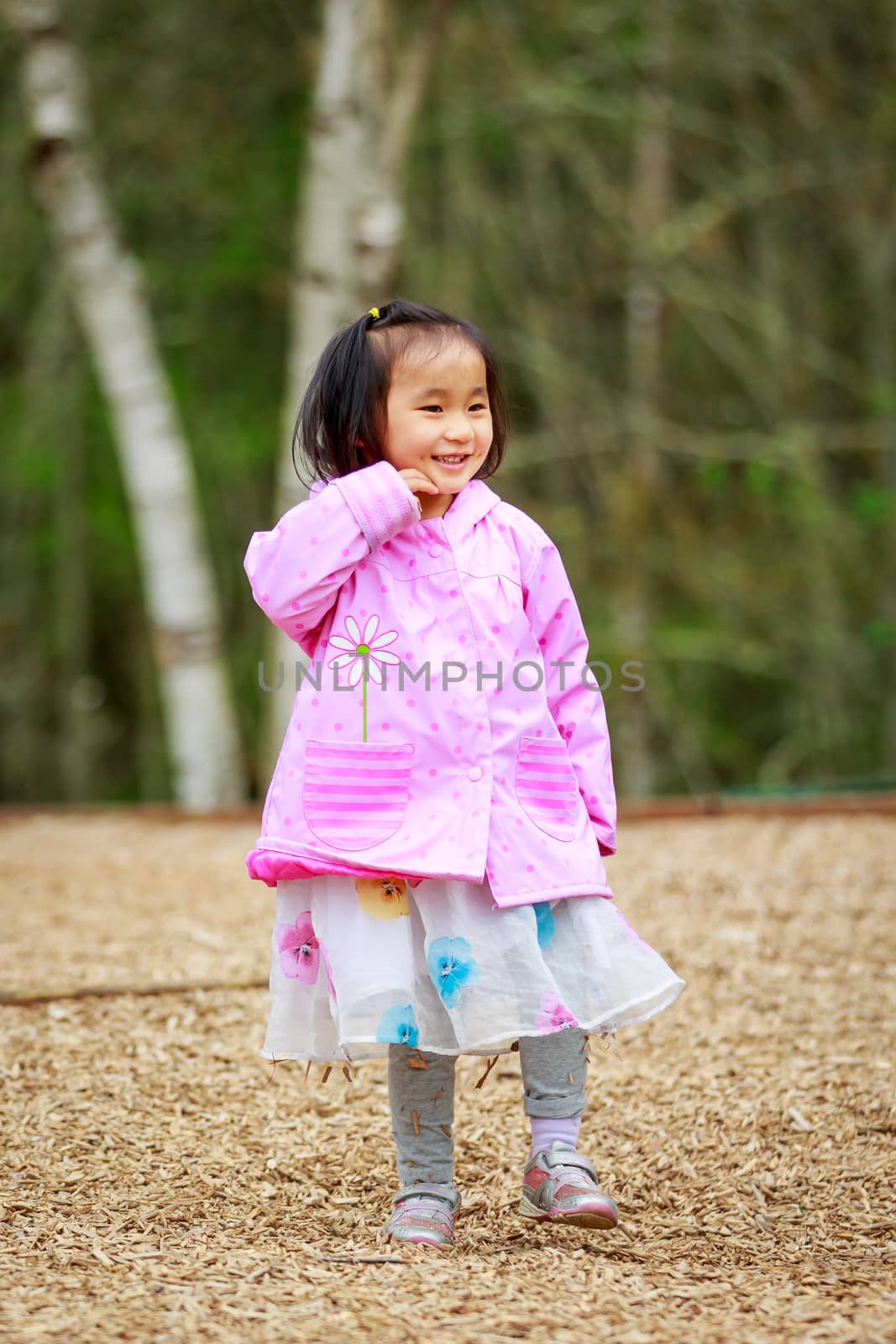 Adorable girl plays in the woods, smiling.