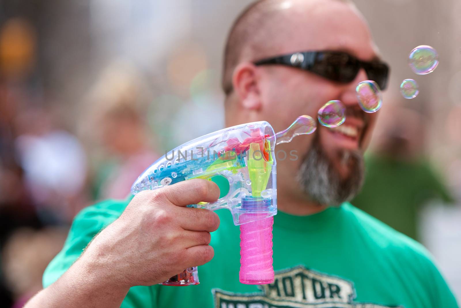Atlanta, GA, USA - March 15, 2014:  A man uses a bubble gun to blow bubbles at the St. Patrick's Day parade on Peachtree Street. 