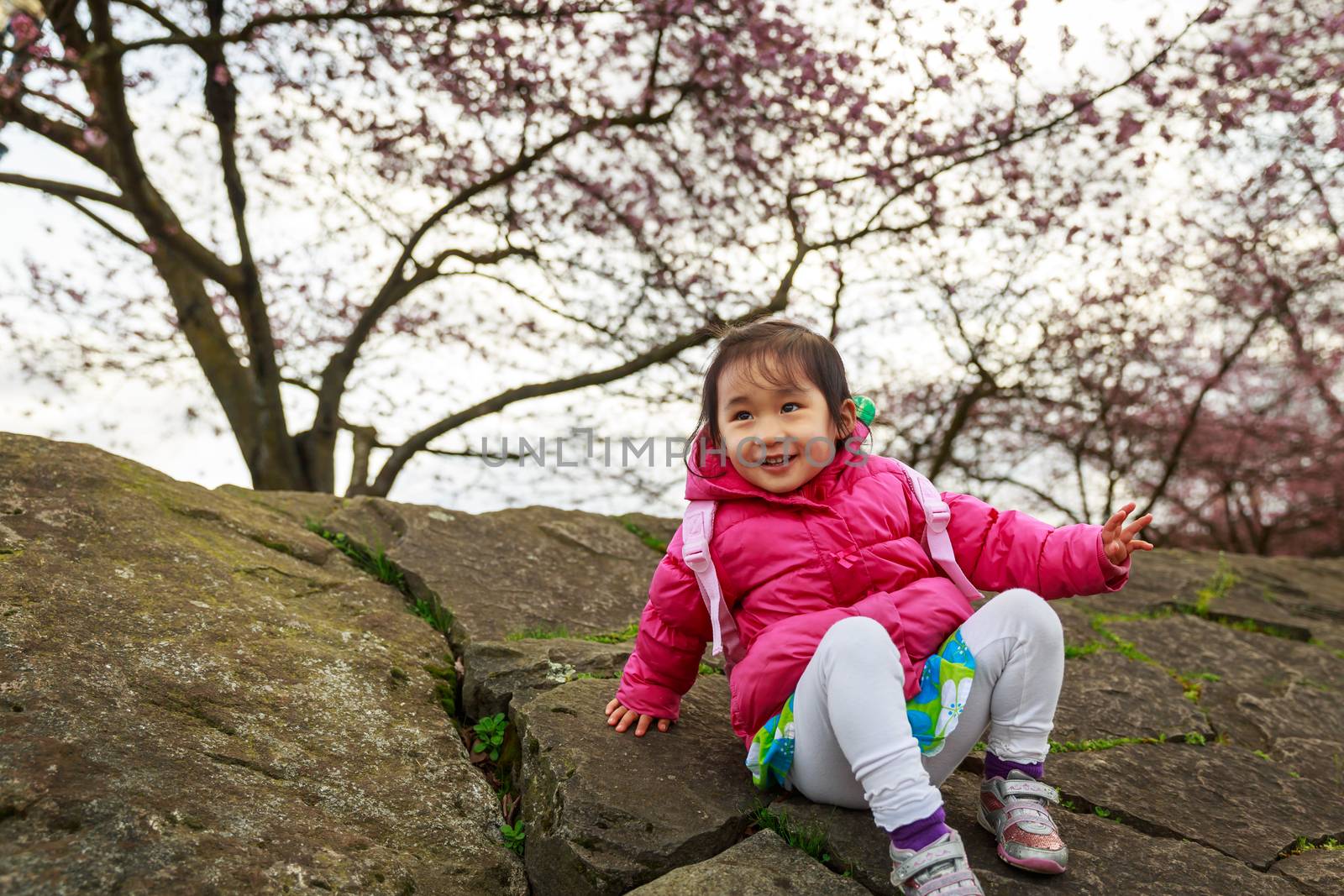 Adorable girl smiles in the woods, play in front of cherry trees