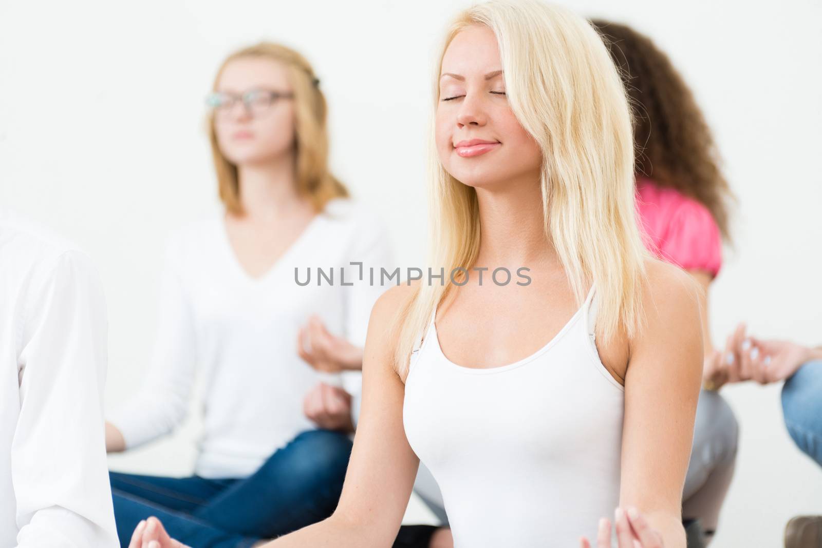 portrait of an attractive young woman, meditating with closed eyes, group meditation