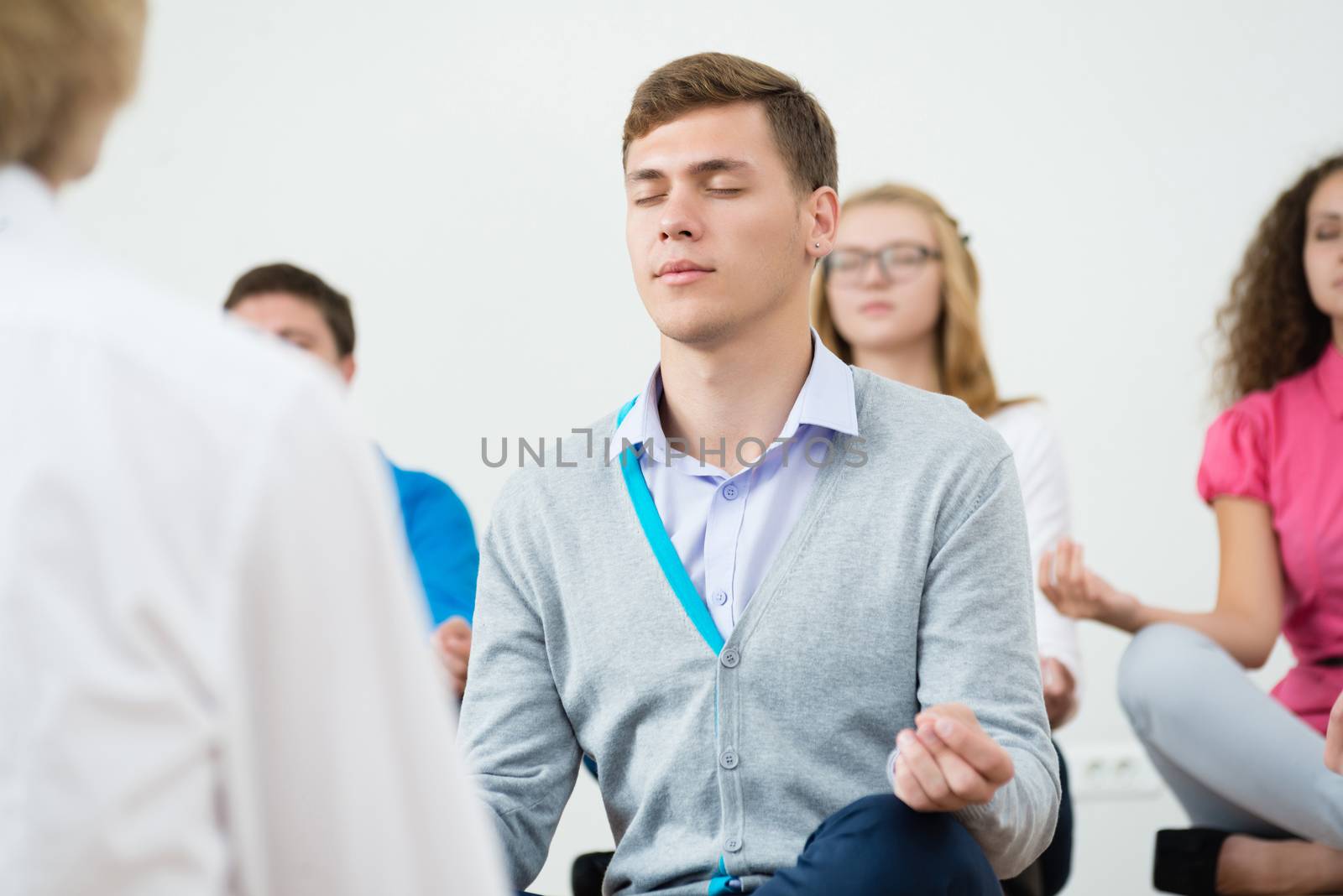 group of young people meditating in office at desk, group meditation