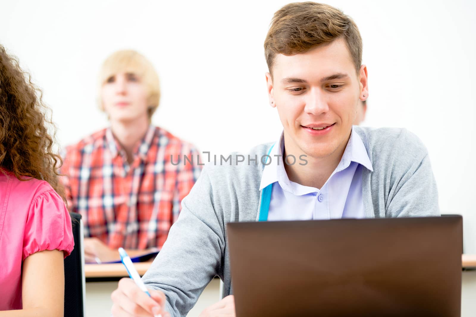 Portrait of a young student in the classroom, working with a laptop