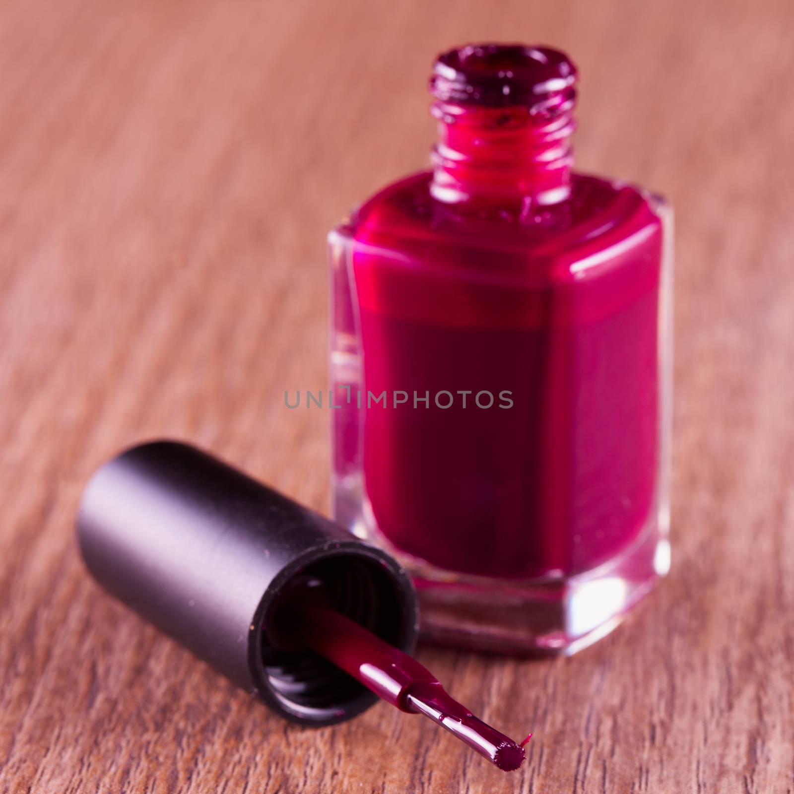 Red nail polish over a wooden background