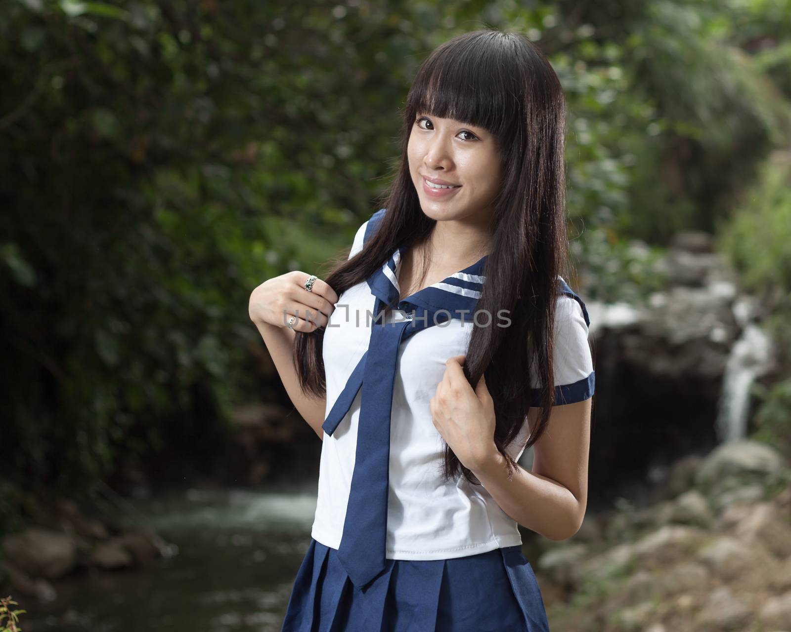 Cute Chinese schoolgirl with waterfall in background