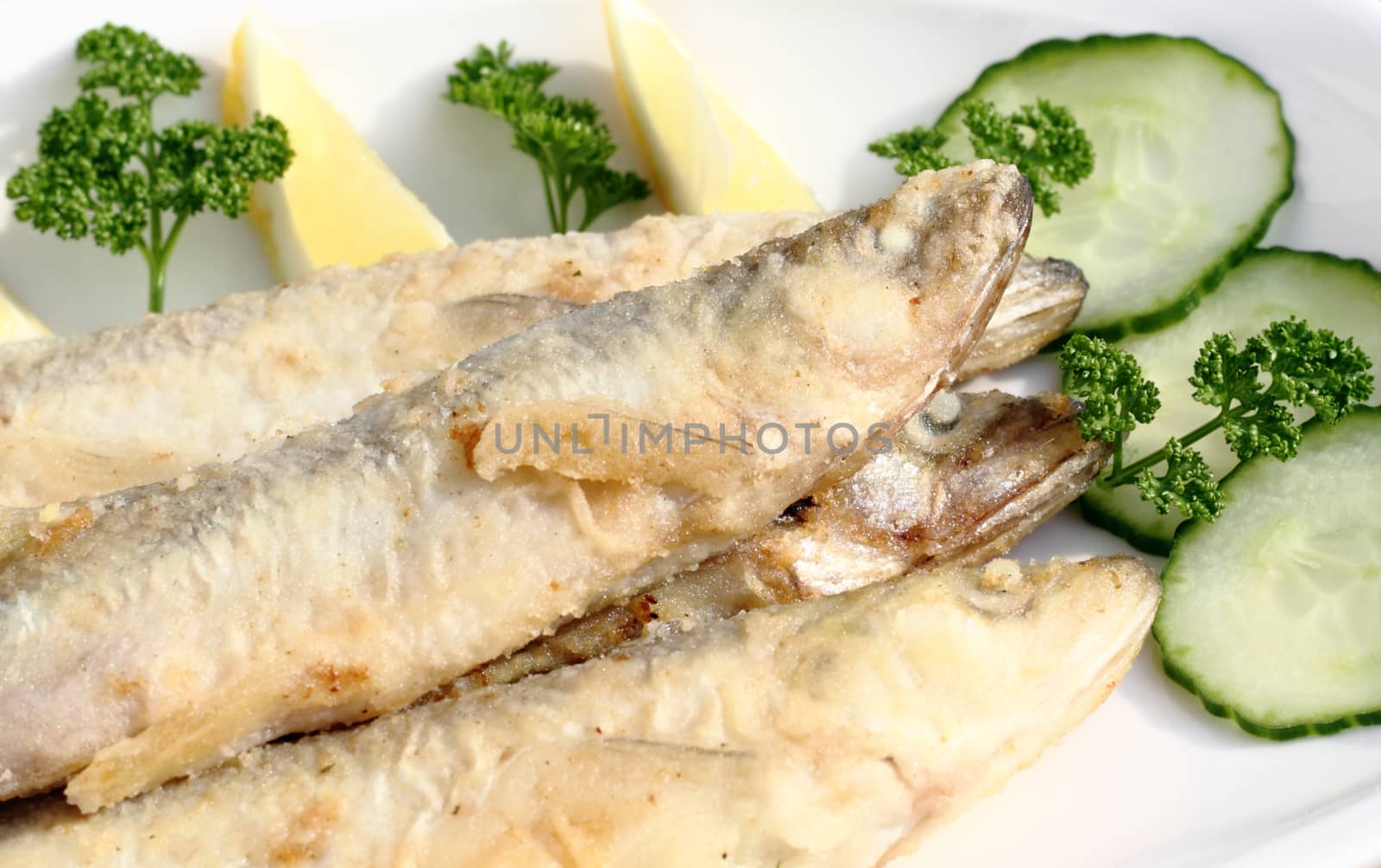 Freshly fried smelt served with cucumber and lemon 