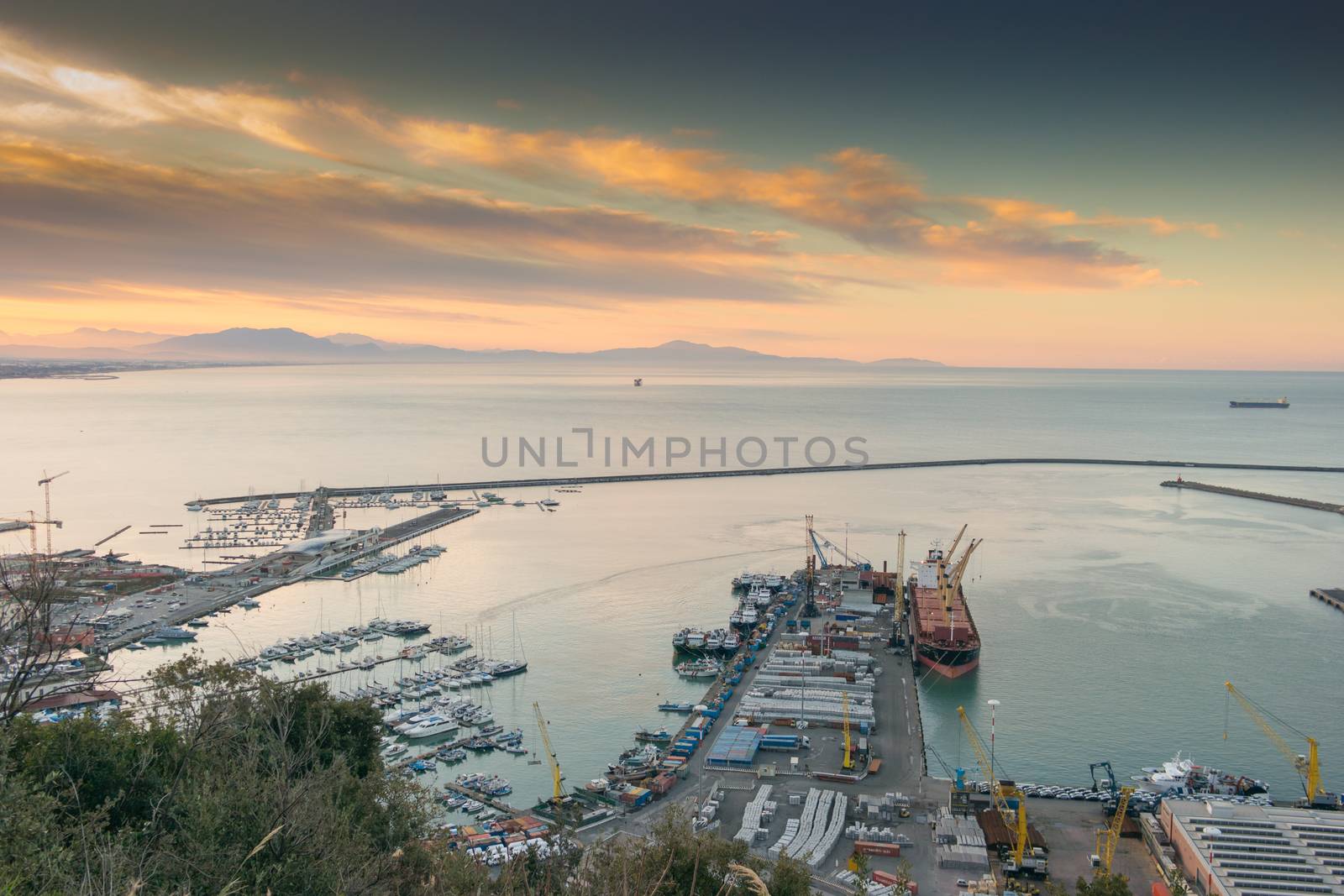 View of the busy harbor of Salerno, Italy, at sunrise with ships and containers on the dock