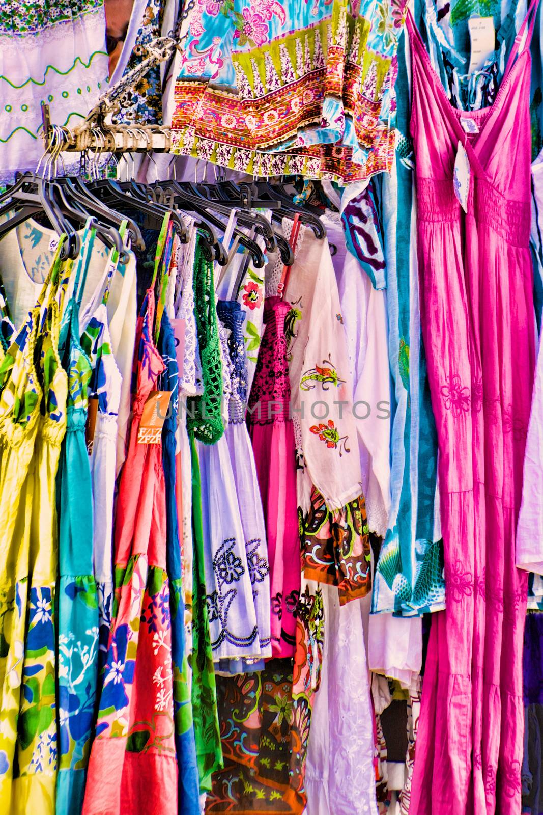 Close-up of women's colorful summer dresses hangin on a market