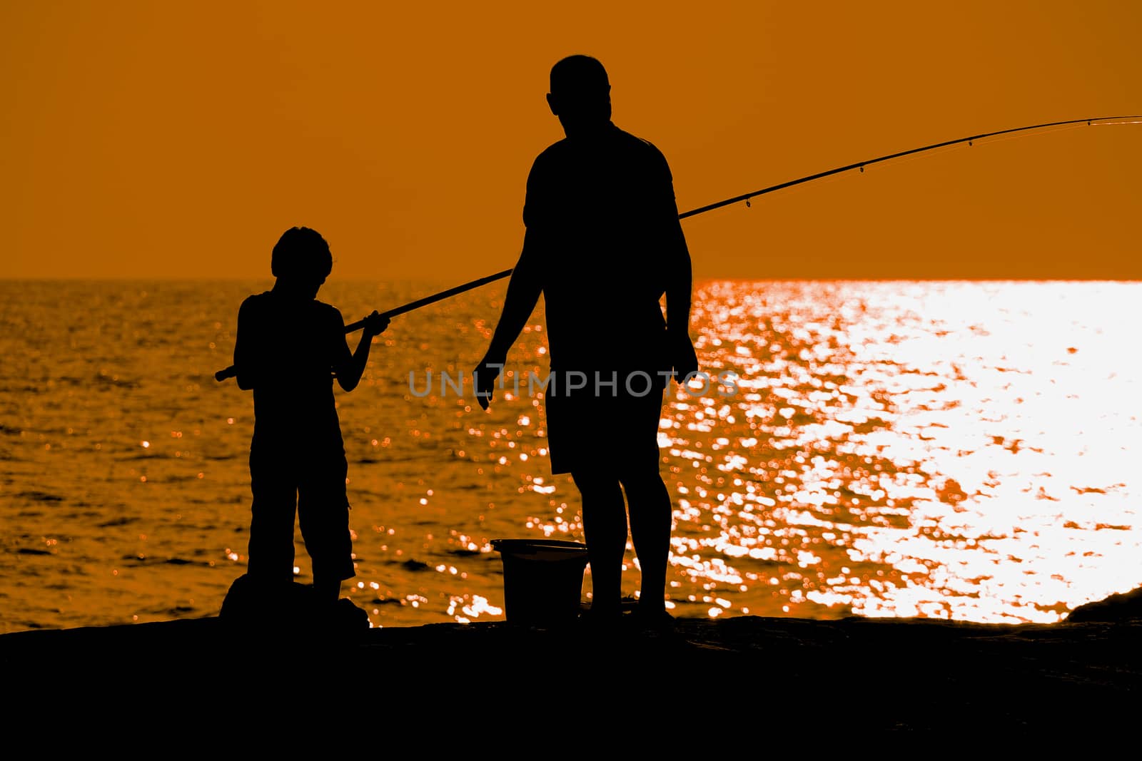 Father and son fishing at dusk silhouette