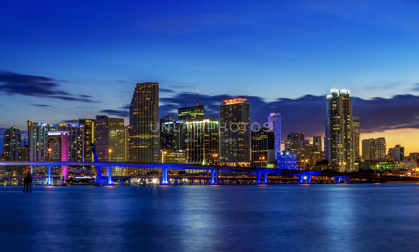 Miami city skyline panorama at dusk with urban skyscrapers over sea with reflection 